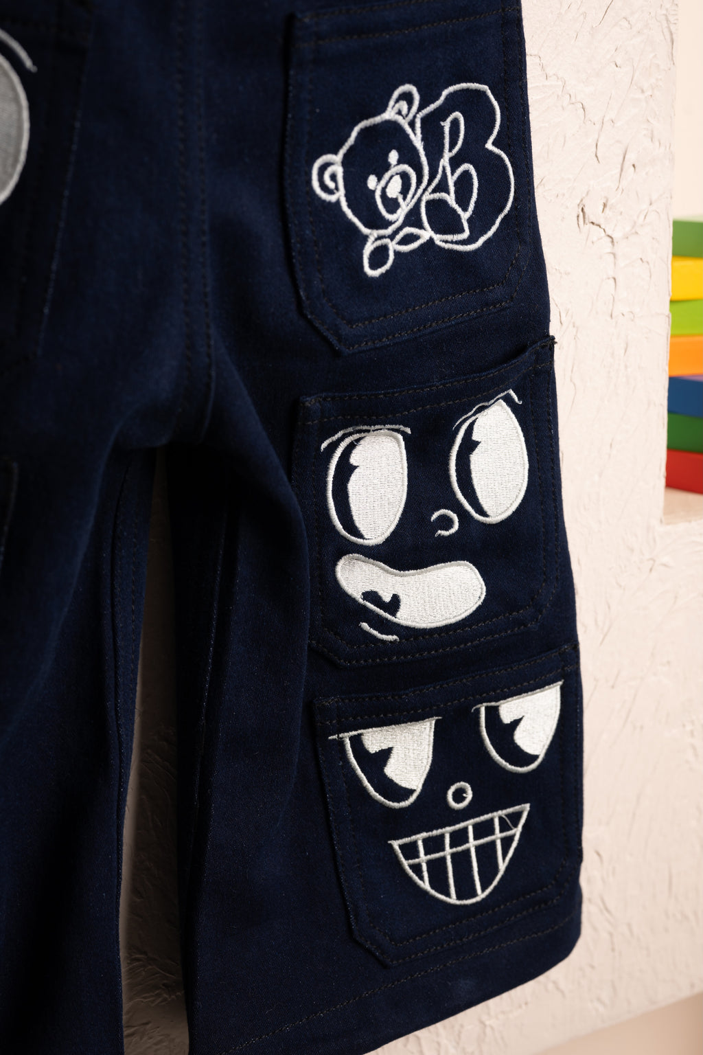Luxurious navy blue pants with embroidered playful cartoon faces and bear patch on pockets