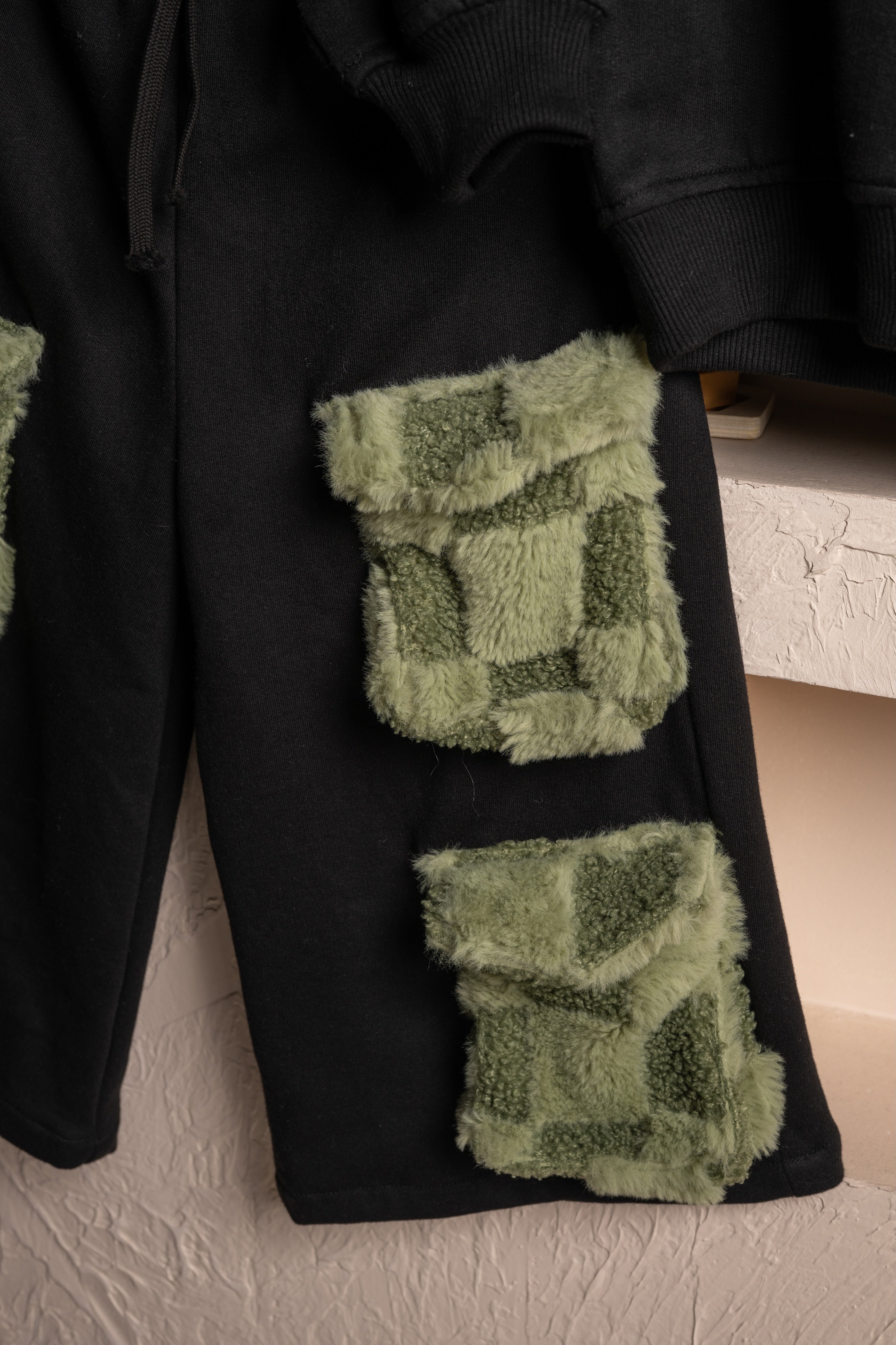 Luxurious black pants with soft green patch pockets featuring plush textured fabric details