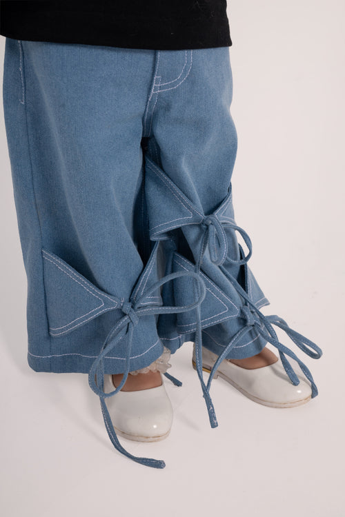 Luxury light blue denim pants with unique bow tie details paired with white patent leather shoes
