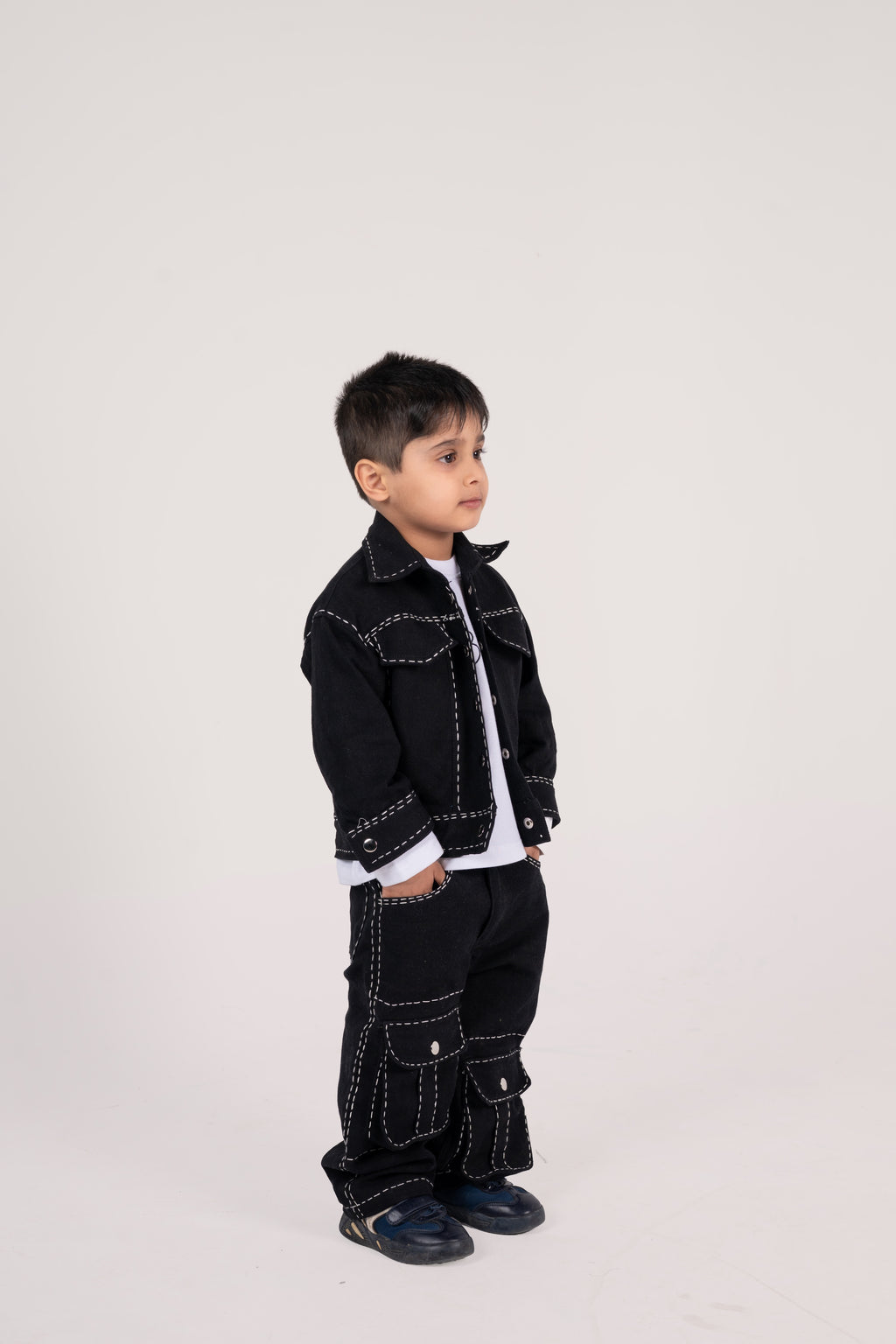 Stylish young boy in black denim jacket and cargo pants with white contrast stitching